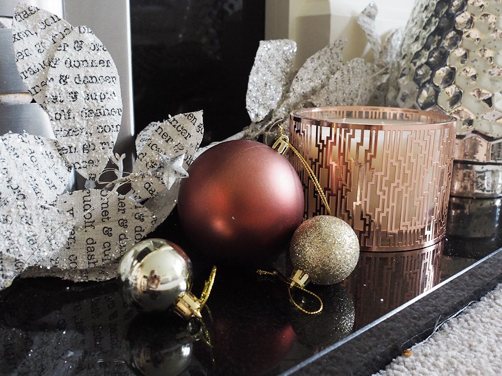 The edge of a fireplace mantle with the start of a black Christmas garland