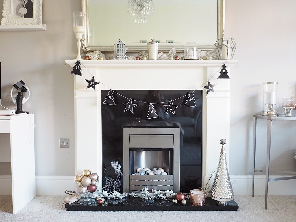 Decorating a Christmas Fireplace A fireplace decorated for Christmas with silver and rose gold accents for a modern look