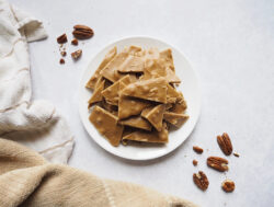 Pecan brittle on a white plate, showcasing the crunchiness and nutty sweetness of the delightful treat.