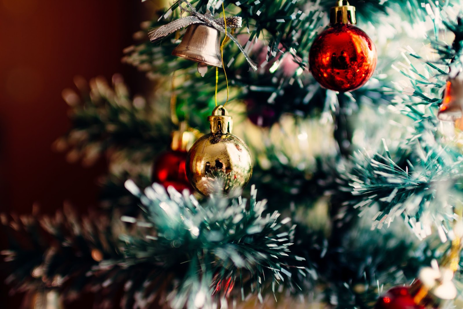 A close up of the branches of an artificial Christmas tree with gold and red baubles