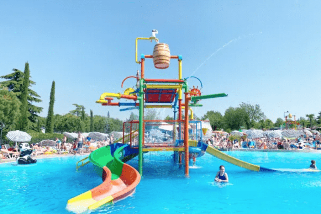 A set of water slides in the middle of a pool in a hotel on a beautiful sunny day with clear skies