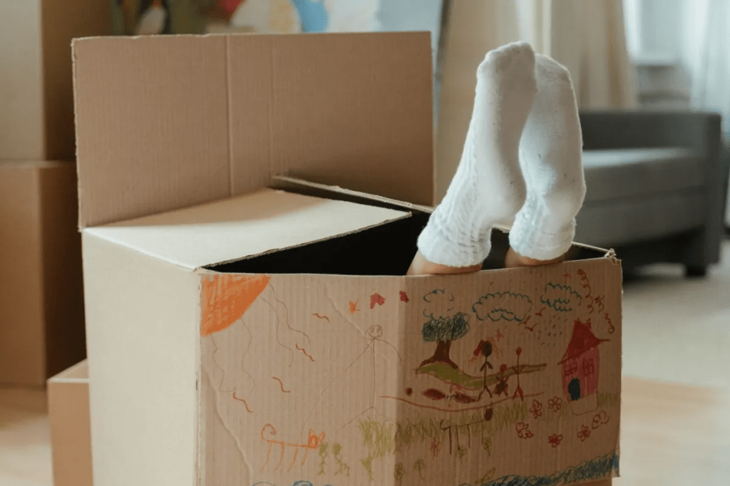 A brown cardboard box with a pair of feet in white socks