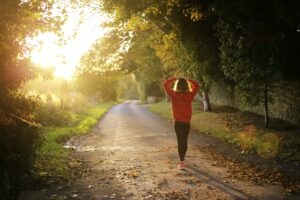 A woman is starting her day, running down a country road with her right foot.