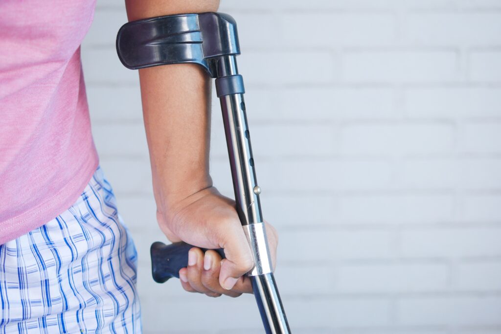 A man wielding a crutch with his hand.