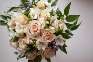 Save time on your wedding day with a stunning bouquet of white roses and green leaves.