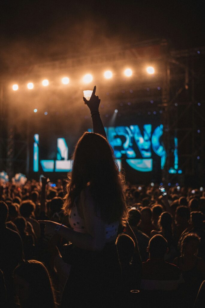 A woman, immersed in the music at an Isle of Wight Festival, enthusiastically raises her hand in the air.