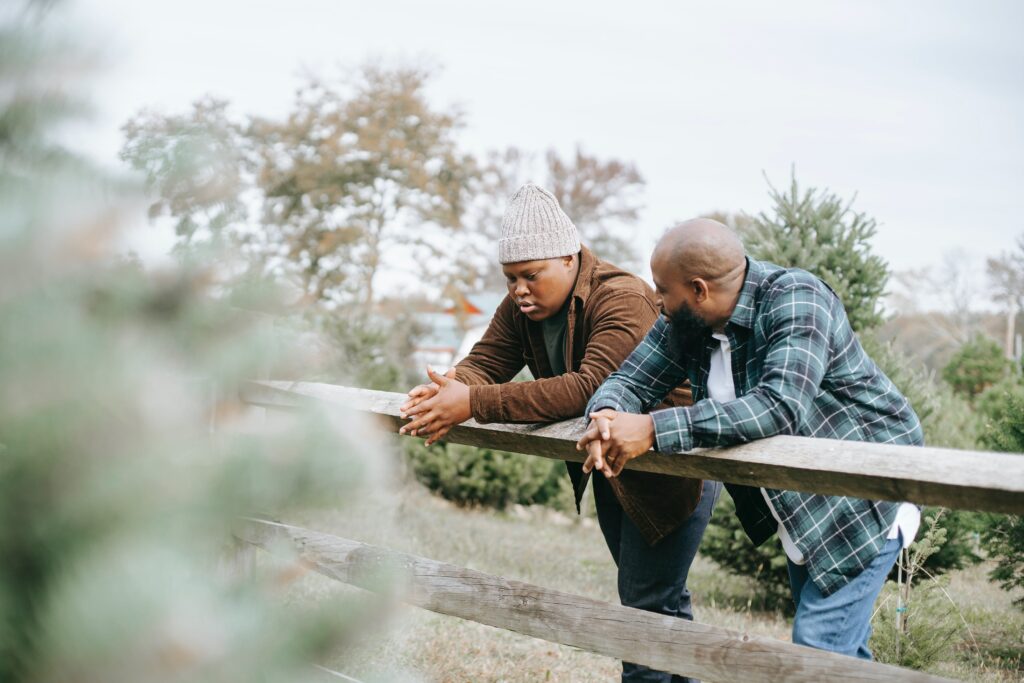 Two parents leaning on a wooden fence.