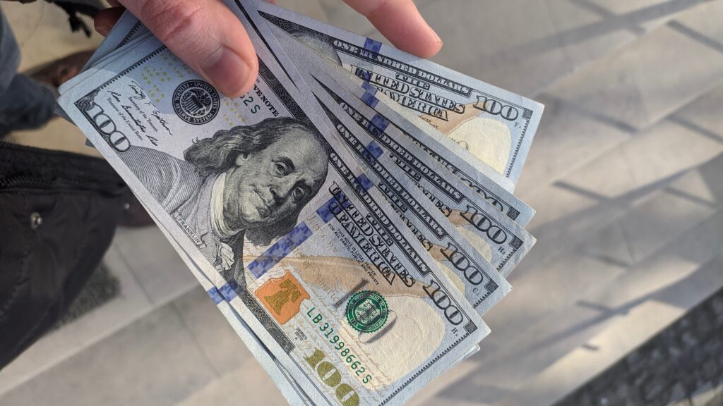 A person holding a stack of dollar bills, showcasing the benefits of Family Trust.