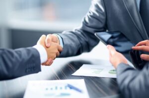 Two business people securing loans by shaking hands over a table.