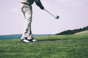 A man is practicing his golf swing on a golf course, seeking tips to improve his technique.