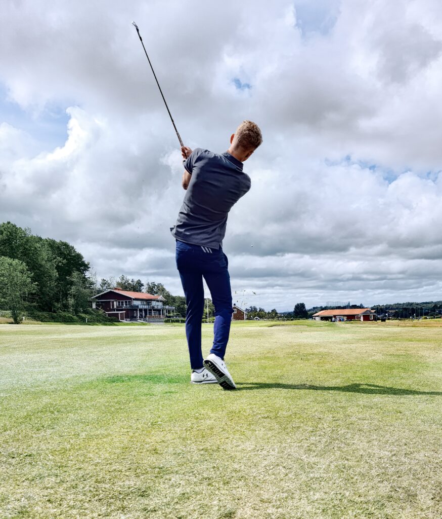 A man improving his golf swing on a green field.