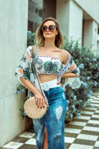 A woman flaunting the latest fashion trends by donning a floral crop top and denim skirt.