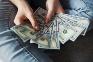 A woman is holding a bunch of money in her hands, turning things around in her financial scenarios.