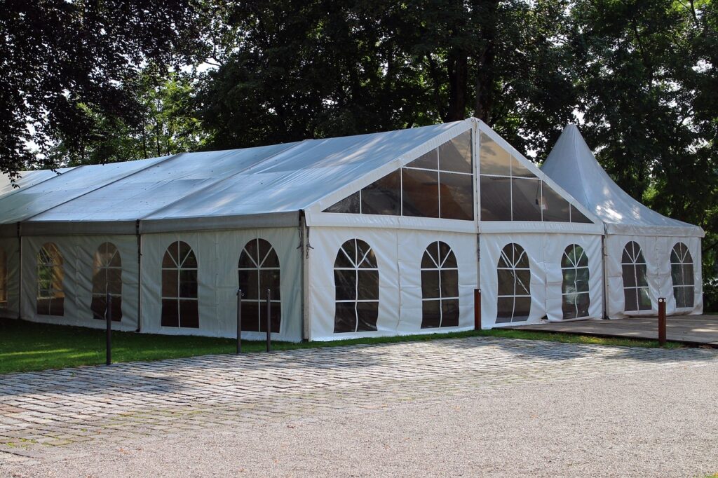 A white tent with windows provides shelter for outdoor events.