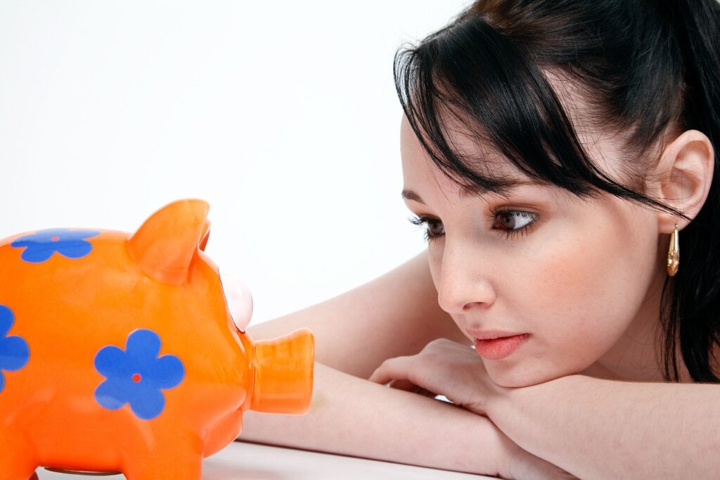 A woman addressing a piggy bank.