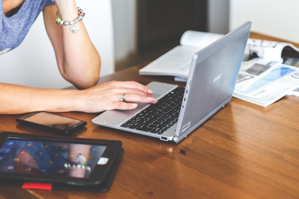 A woman addressing a common faux pas by sitting at a table with a laptop and cell phone.