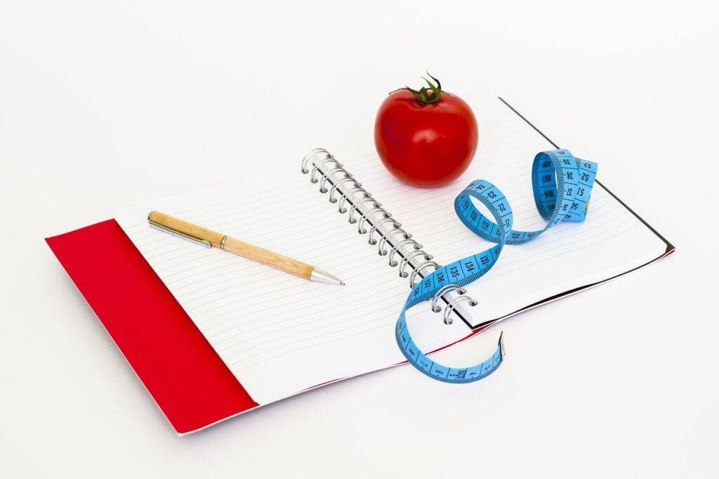 A notebook with a measuring tape, essential for losing weight.