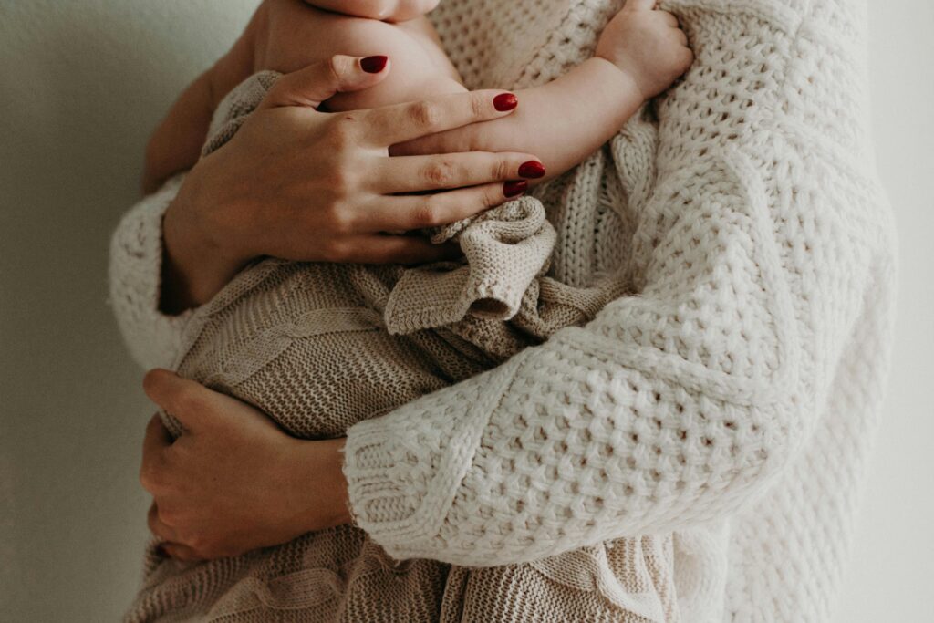 A woman holding a baby in a sweater, on maternity leave.