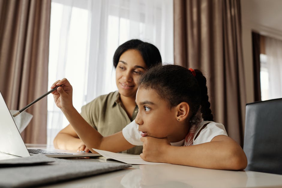 A mother and daughter working on a laptop at home.