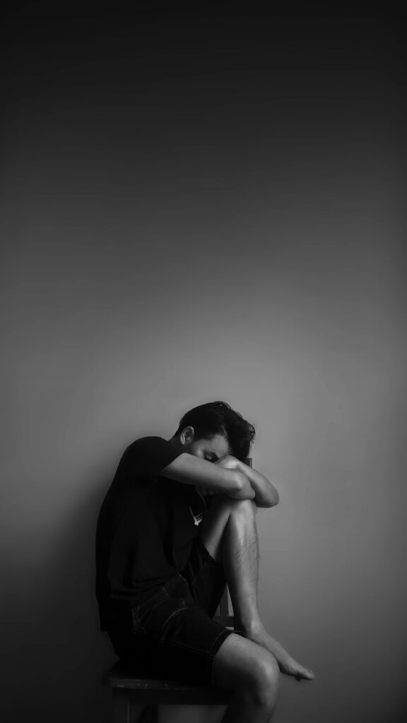 A black and white photo of a man sitting on a chair, conveying the impact of depression on life.