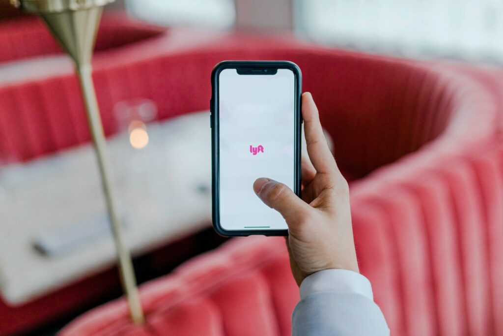 Person holding a smartphone displaying the Lyft logo on the screen, promoting ridesharing services to drive to earn.