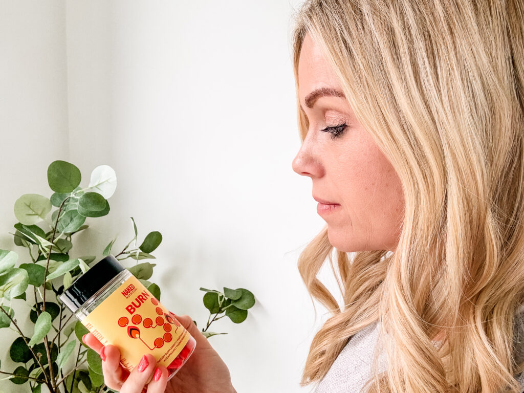 A blonde woman holding a jar of honey.