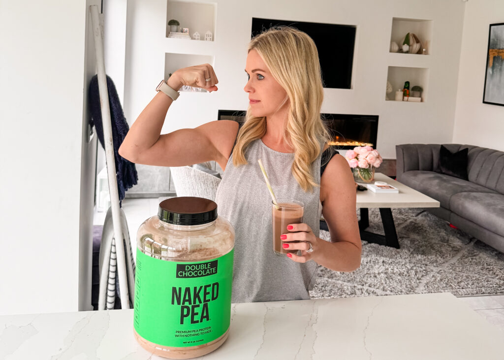 A woman posing in front of a jar of pea protein.