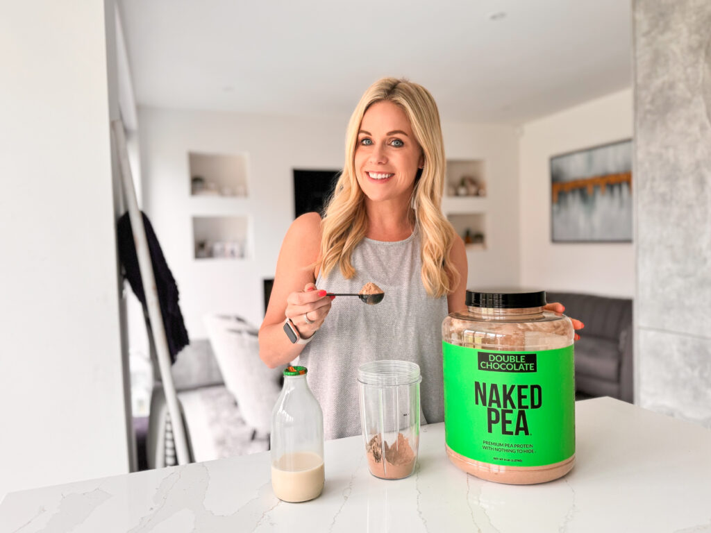 A woman standing in front of a jar of naked ice, made with pea protein.