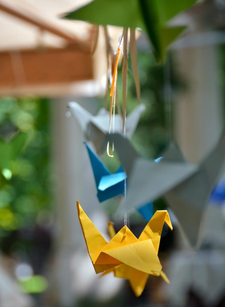 Colorful paper cranes, embodying Japanese aesthetics, hanging as part of a mobile decoration.