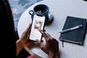 Person browsing Instagram tricks on a smartphone with a cup of coffee and a notebook on the table.