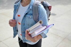 A student carrying a backpack and books.